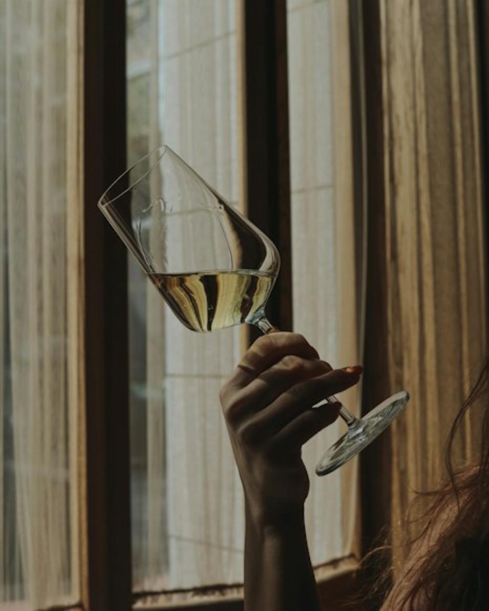 Un verre de vin blanc tenu par une femme